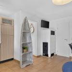 Küche mit Holzschränken, Esstisch mit Stühlen und Kaminofen mit Fernseher.