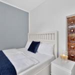 Schlafzimmer mit weißem Bett, blauer Decke und Holzfliesenwand