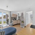 Wohnbereich mit Küche, Schlafzimmer und Terrasse. Modern eingerichtet mit Sofa und Esstisch.