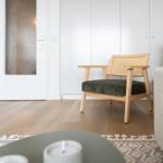 A chair with a green seat and wooden frame is in the living room.