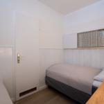 Bedroom with bed, desk, and door. Wall paneling and decorative element.