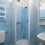 Bathroom with shower, sink, and toilet. Walls are covered with blue tiles.