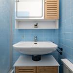 Bathroom with blue tiles, sink, and mirror cabinet.