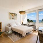 A bedroom with sea view, furniture and wall art are visible.