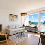 Living area with sofa, dining table, and balcony with sea view.
