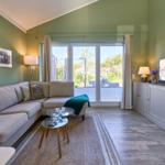 Wohnzimmer mit Sofa, TV und Blick auf Balkon.