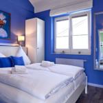 Schlafzimmer mit blauen Wänden, Bett, Spiegel und Fenster.