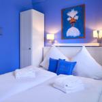 Schlafzimmer mit blauen Wänden, Bett mit Kissen und Wandbild eines Vogels.