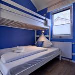 Zimmer mit Doppelstockbett, blauen Wänden und Fenster mit Blick nach draußen.
