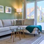 Ein Wohnzimmer mit Sofa, Tisch und Blick auf Balkon.