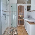 Badezimmer mit Dusche, Waschbecken und Sauna.