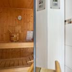 Sauna mit Holzwand, Sitzbänken und Thermometer. Steuerung an der Tür.