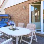 Terrasse mit weißem Tisch, Stühlen und Liegestuhl vor Backsteinhaus