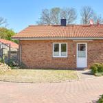 Einzelne Villa mit rotem Dach und Backsteinfassade. Vorgarten mit Steinmauer und gepflastertem Weg.