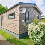 Moderne Ferienwohnung mit Satellitenantenne und Blumenhecke im Grünen.