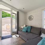 Wohnzimmer mit Sofa, Fenster und Terrasse. Holzwand und moderne Einrichtung.