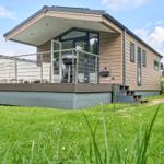 Moderne Ferienhaus mit Terrasse, Grill und grünem Garten.