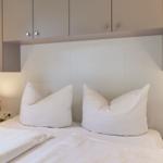 Schlafzimmer mit Bett, zwei Kissen und Nachttischen mit Lampen.