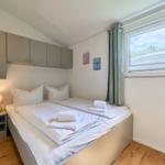 Schlafzimmer mit Doppelbett, Nachttisch, Fenster und Schränken.
