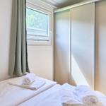 Schlafzimmer mit Bett, Fenster und Kleiderschrank. Auf dem Bett liegen Handtücher.