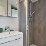 Badezimmer mit Dusche, Waschbecken und Spiegelschrank.