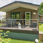 Holzhaus mit Terrasse, Grill und Sitzgelegenheiten im Grünen.