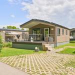 Mobile Home mit Terrasse, Grill und Garten. Modernes Design mit Holzfassade und Glasfront.