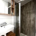 Badezimmer mit Dusche, Waschbecken und Spiegelschrank.