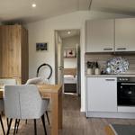 Küche mit Essbereich und Blick in Schlafzimmer. Holzmöbel und moderne Geräte.