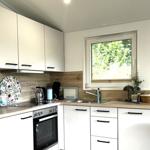 Küche mit weißen Schränken, Holz Arbeitsplatte und Fenster zum Garten.