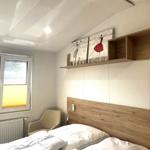 Schlafzimmer mit Bett, Fenster, Stuhl und Wandregal mit Bildern.