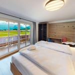 Schlafzimmer mit Balkon und Bergblick. Bett, Schreibtisch und Kleiderständer.
