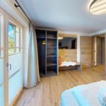 Schlafzimmer mit Bett, Kleiderschrank und Blick auf die Berge.