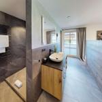 Badezimmer mit Dusche, Waschbecken und Fenster zur Aussicht.
