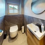 Badezimmer mit Toilette, Waschbecken und Fenster mit Aussicht.
