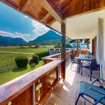 Terrasse mit Sitzgelegenheiten und Blick auf grüne Wiesen und Berge.