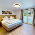 Schlafzimmer mit Holzbett, Fenster und Wandbild.
