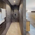 Dusche mit Duschbrause, Handtuchhalter und Steinwand