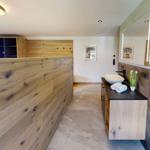 Bad mit Holzwand, Waschtisch und Spiegel. Fliesenboden und moderne Einrichtung.