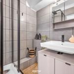 Badezimmer mit Dusche, Waschbecken und Spiegelschrank.