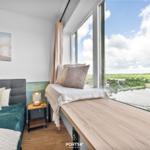 Schlafzimmer mit Blick auf Wasser und Landschaft. Bett, Fensterbank und Wandbild.