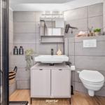 Badezimmer mit Dusche, Waschbecken und Toilette. Graue Fliesen und Holzboden.
