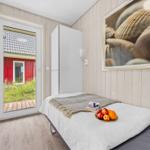Schlafzimmer mit Bett, Schrank und Tür zum Garten. Wandbild mit Muscheln.