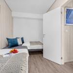 Zimmer mit zwei Betten, Holzwand und Bildern an den Wänden.