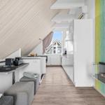 Dachgeschosswohnung mit moderner Küche, Sitzgelegenheiten und Wandkamin.