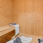 Sauna mit Holzwandverkleidung, Sitzbänken und Handtüchern.