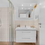 Badezimmer mit Dusche, Waschbecken und Spiegel