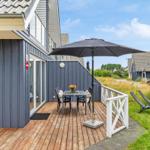 Terrasse mit Tisch, Stühlen und Sonnenschirm neben einem Haus mit Holzverkleidung.