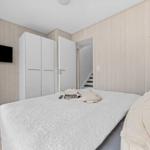 Schlafzimmer mit Bett, Kleiderschrank und Fernseher an der Wand.