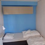 Schlafzimmer mit zwei Betten, blauer Wand und Schrank.